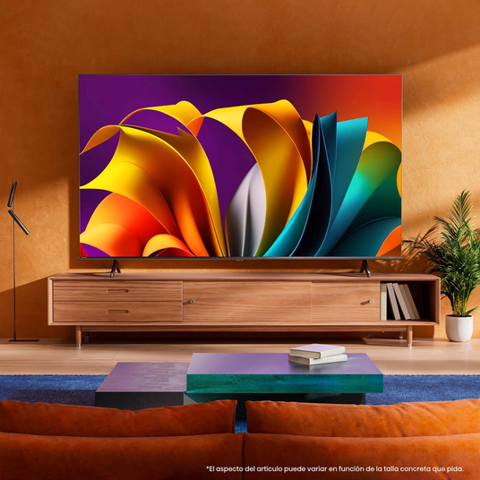 TV grande mostrando arte abstracto, sobre muebles de madera. Una mesa azul y verde al frente.
